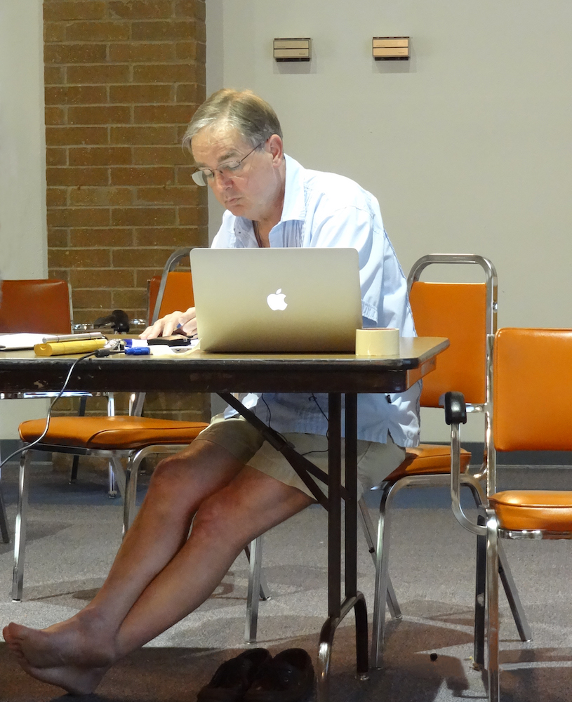 Gene Bebeau Volunteering with WCCM-USA, in bare feet, working on a computer.